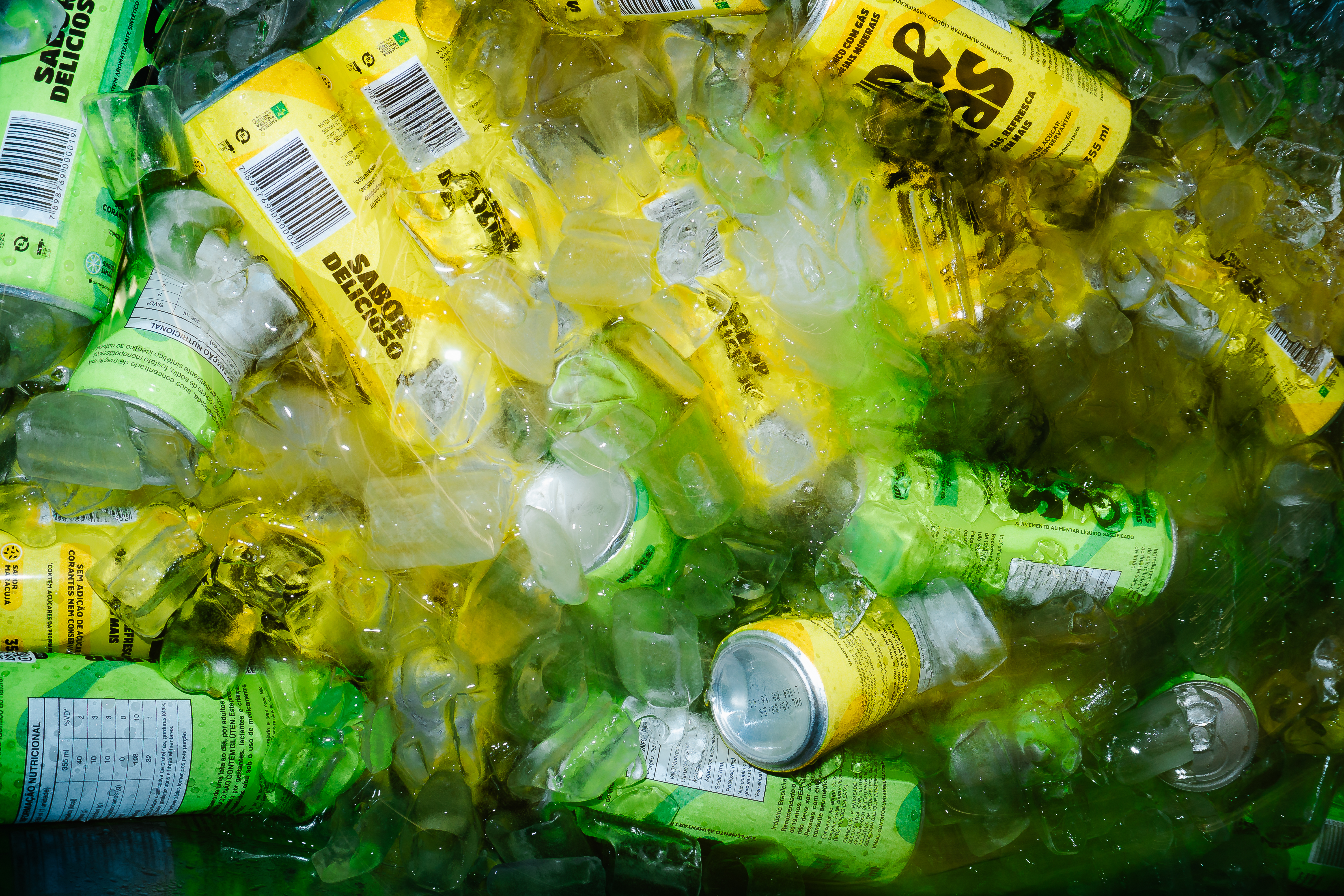 Três latas de Zuzzi Brisa Tropical posicionadas sobre cubos de gelo